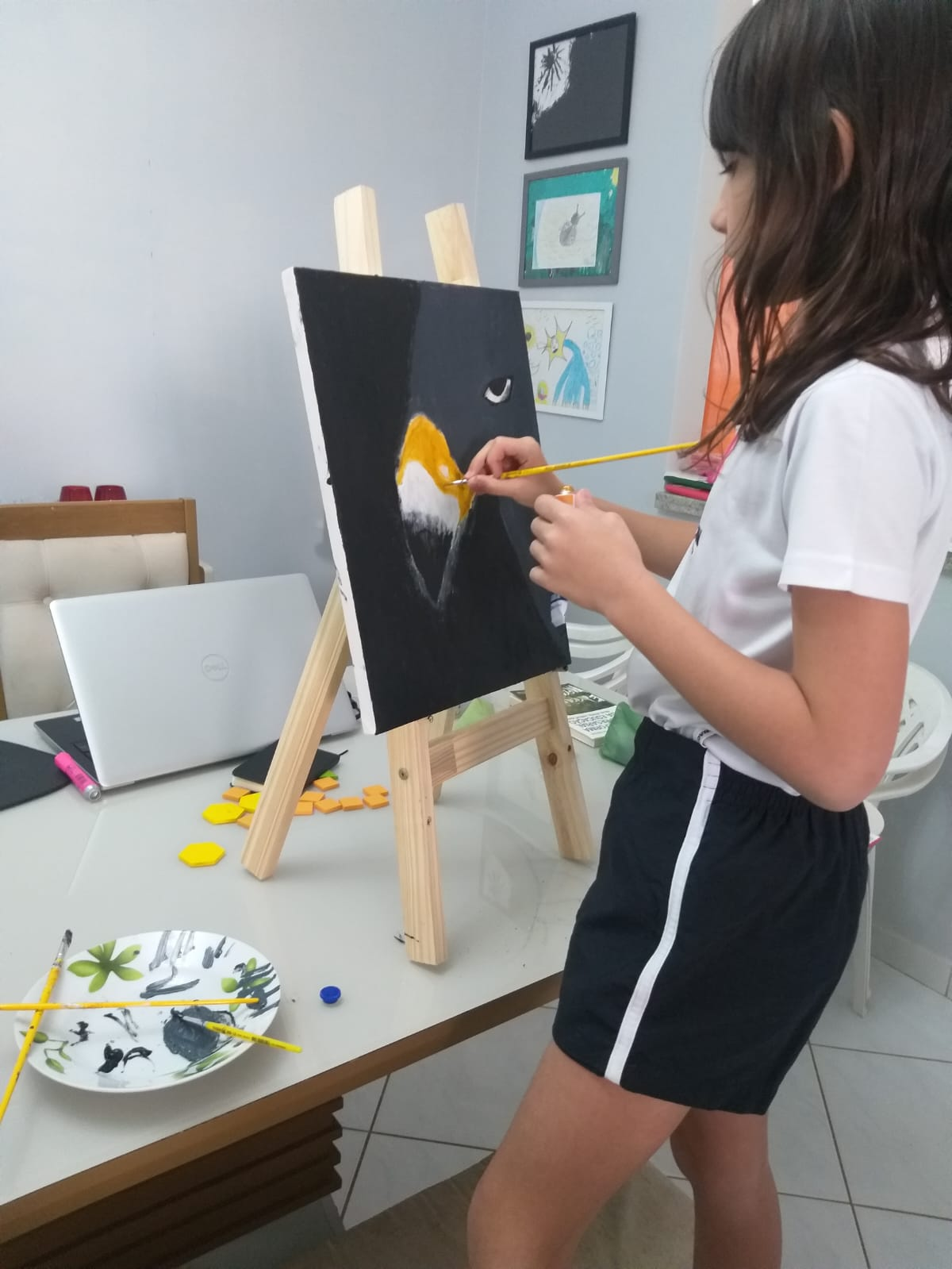 Helena, criança, pintando o bico amarelo da águia no cavalete