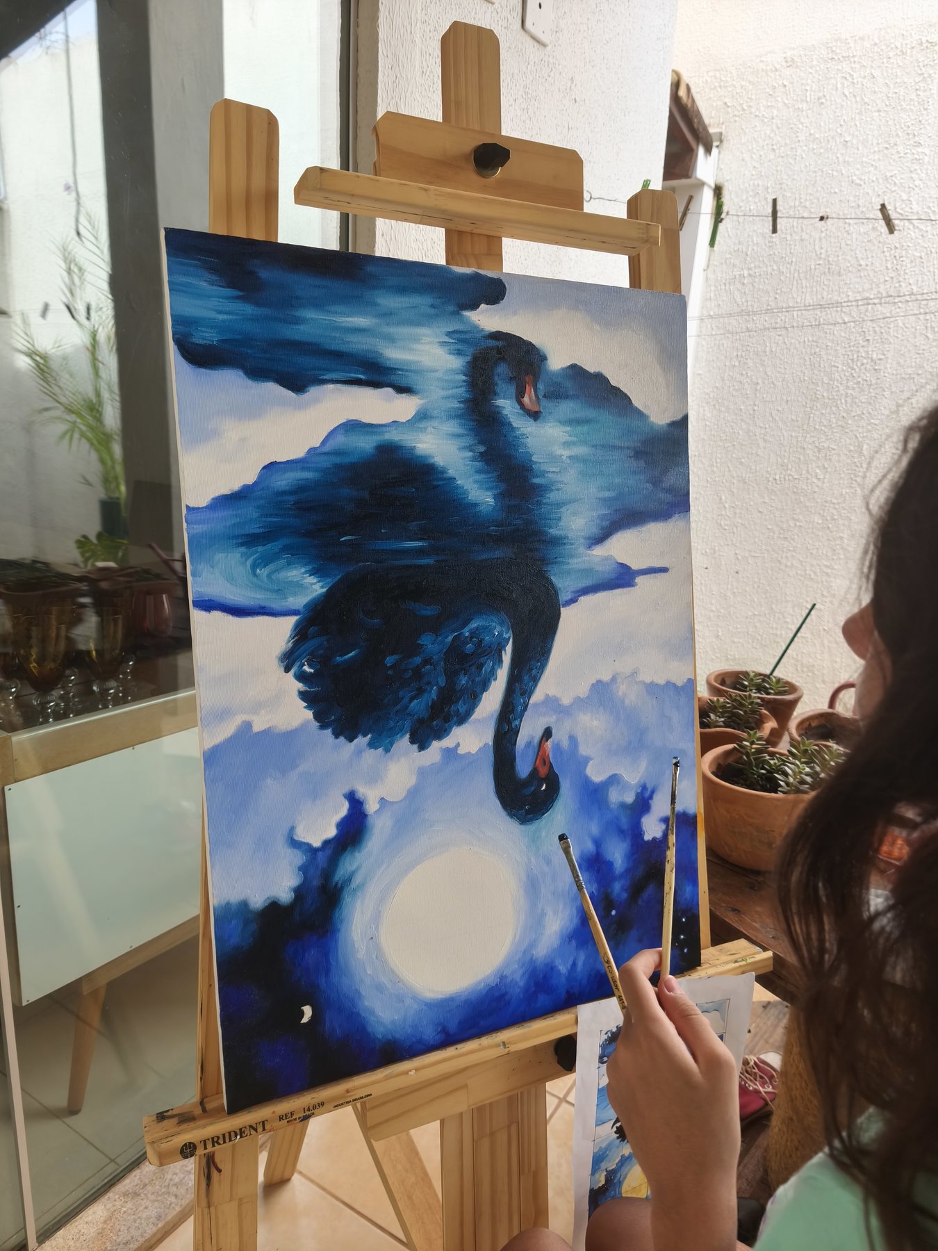 Helena pintando o cisne azul na tela no cavalete